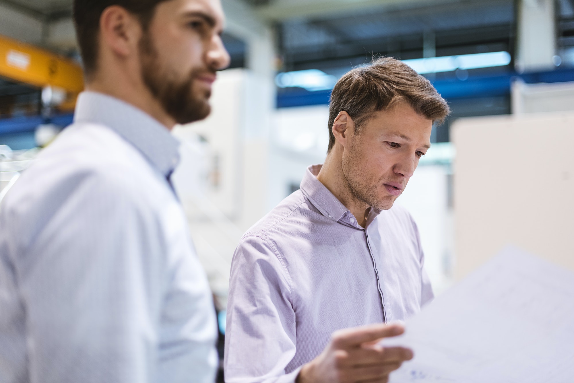 Two men in factory looking at plan