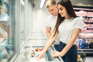 Young couple choosing frozen goods in supermarket